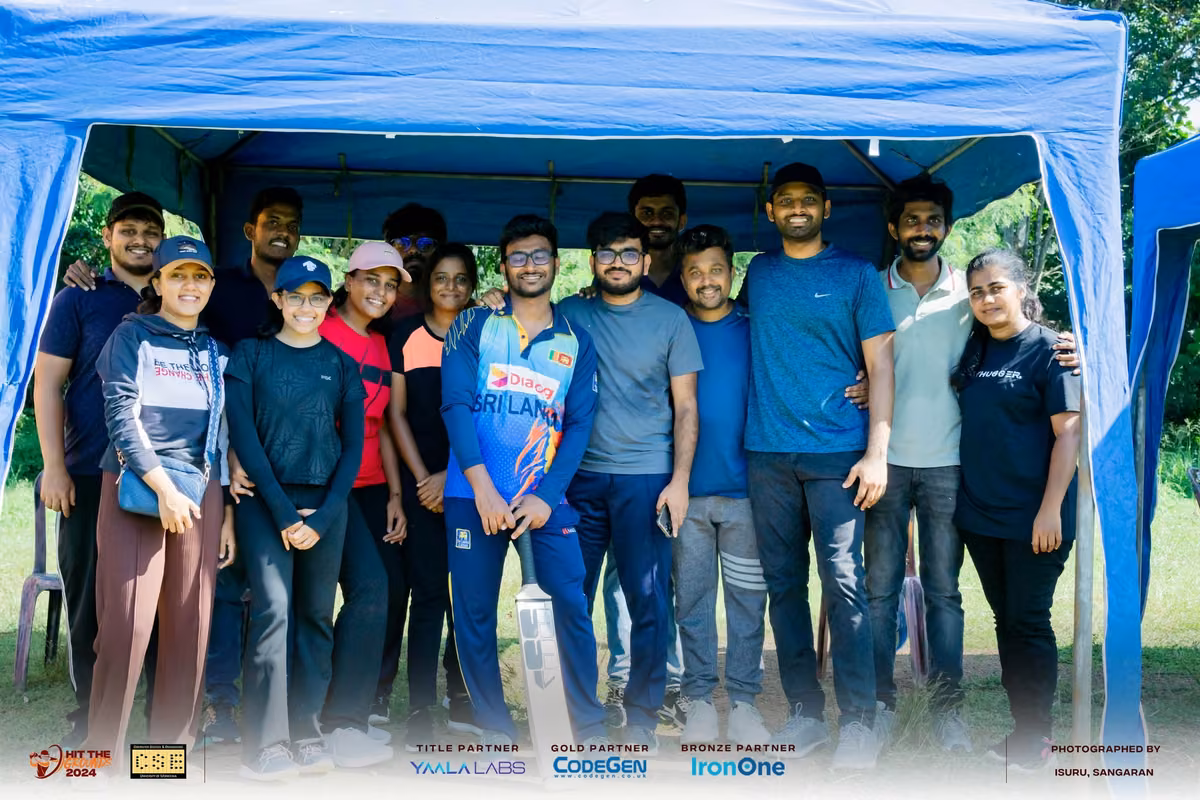 A large group posing together under a blue tent