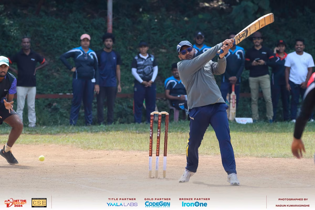 A batter playing a shot in front of the sidelines