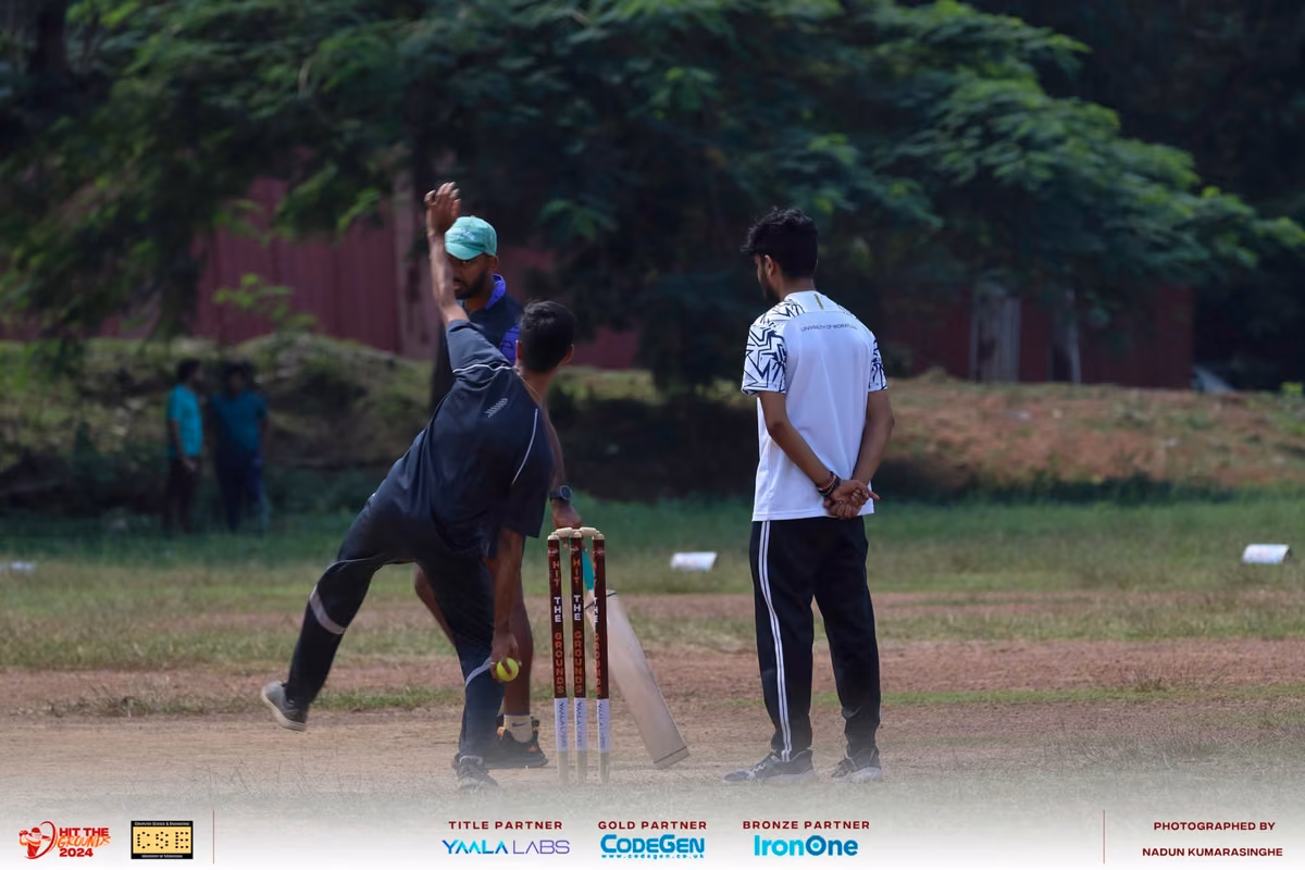 A bowler in dark kit delivering the ball with an umpire behind