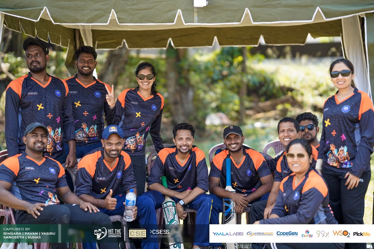A team in navy and orange jerseys posing together under a tent