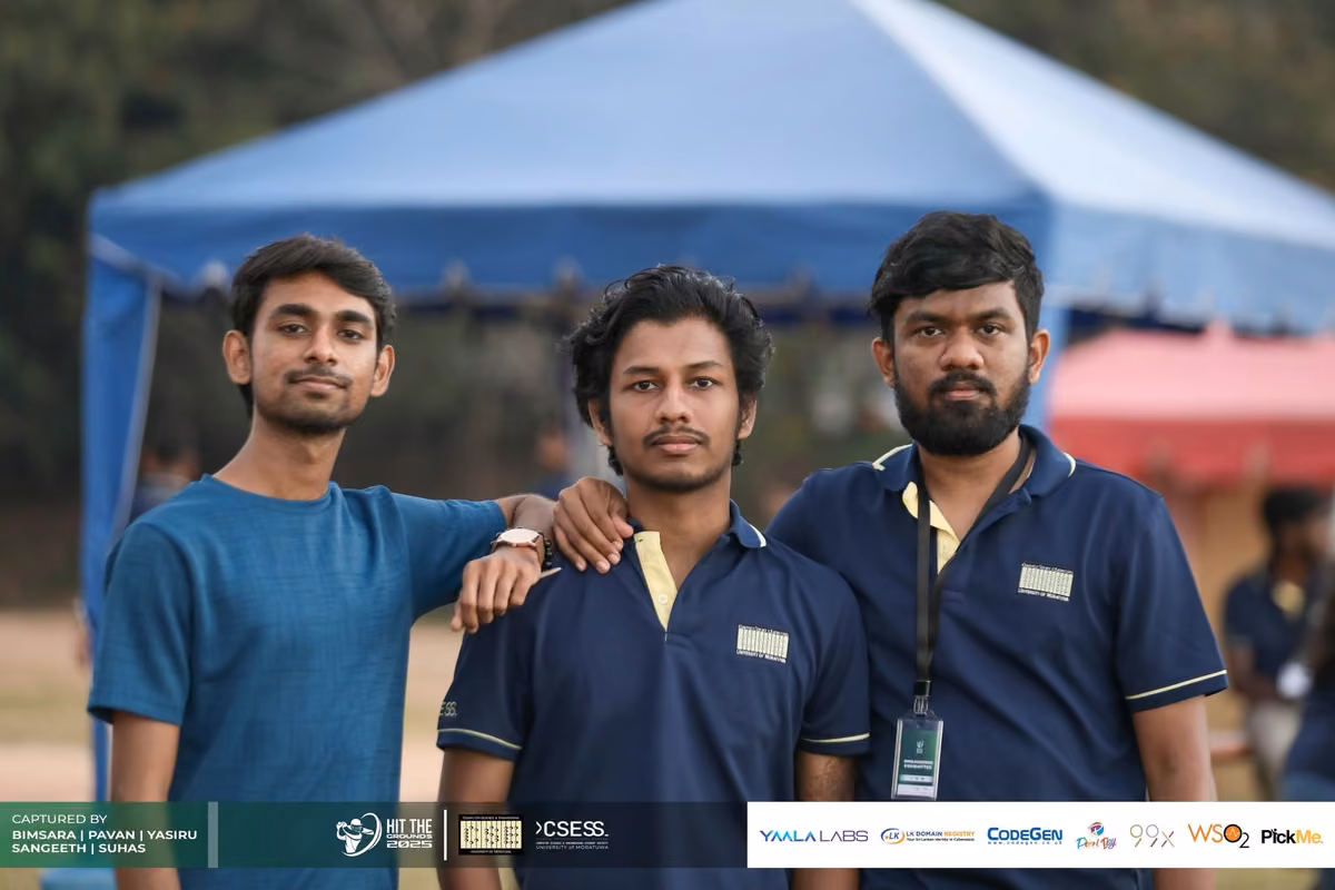 Three men in navy polos posing under a blue tent